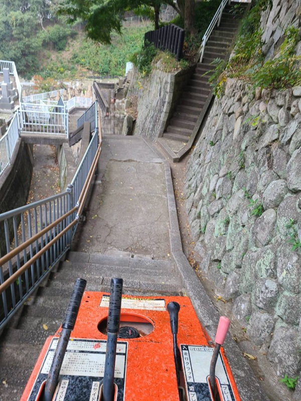 神戸市の追谷墓園で長い階段を小型運搬車により墓石搬出する様子