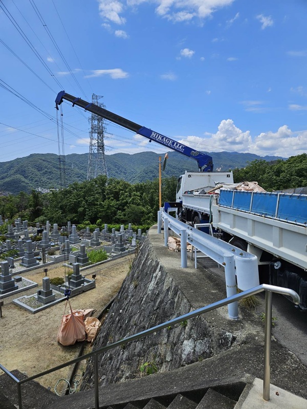 高低差のある墓地でクレーン車を使用して石材を搬出する様子